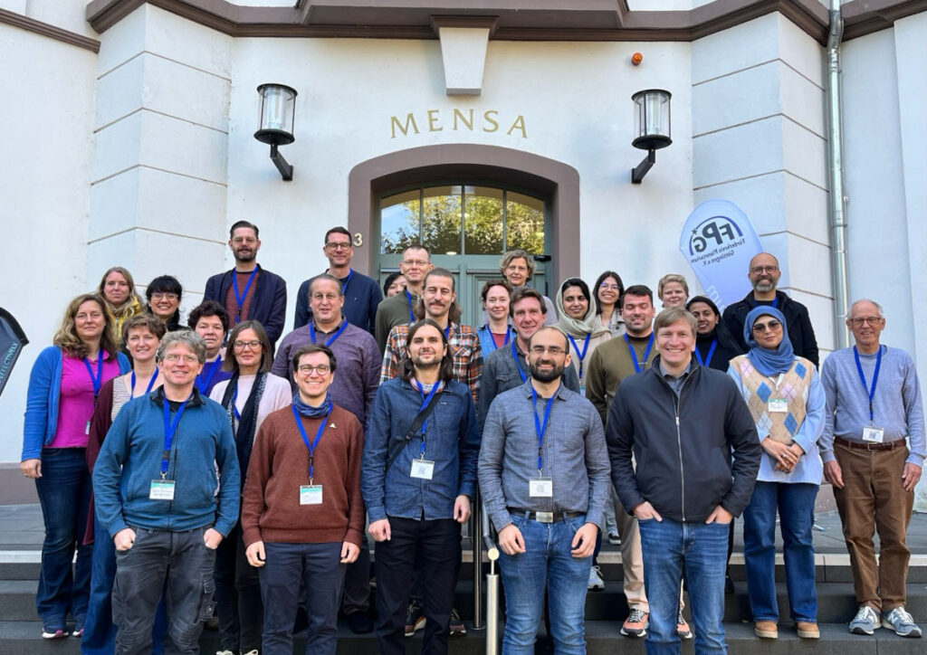 Group photo of about 30 scientists, standing on stairs in front of a historic building